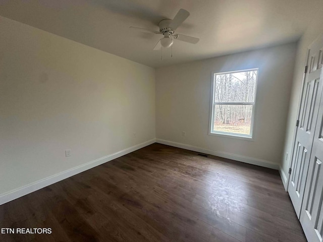 empty room with ceiling fan and dark hardwood / wood-style flooring