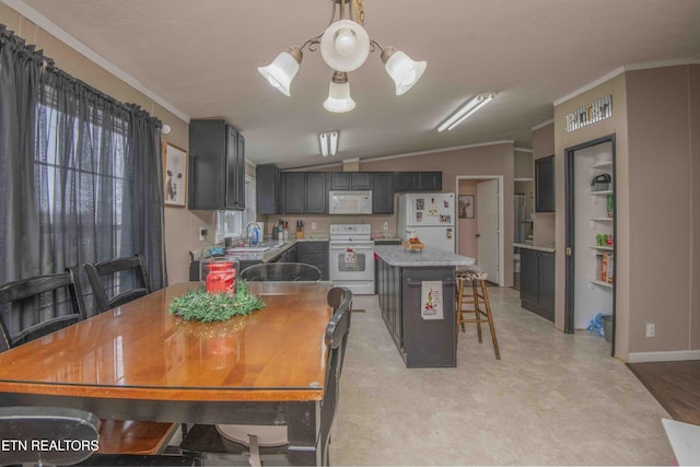 dining space featuring vaulted ceiling, sink, crown molding, and a chandelier