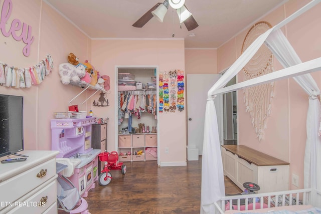 bedroom with a crib, ceiling fan, dark hardwood / wood-style floors, and ornamental molding