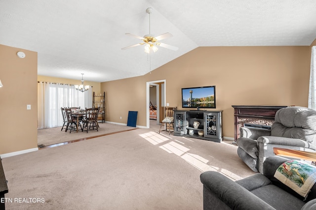 carpeted living room with ceiling fan with notable chandelier and vaulted ceiling