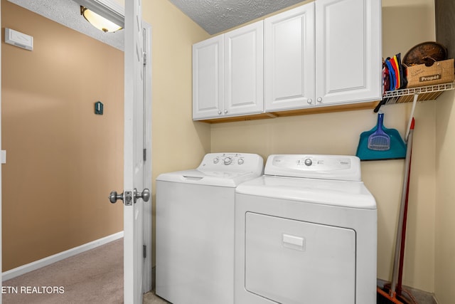 clothes washing area featuring cabinets, washing machine and dryer, light colored carpet, and a textured ceiling