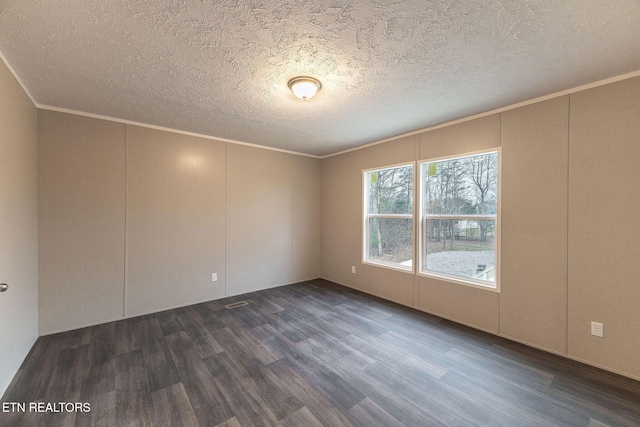 spare room with a textured ceiling, crown molding, and dark wood-type flooring