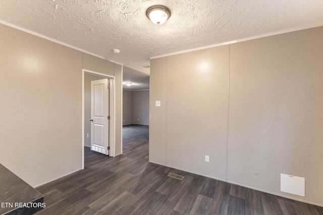 empty room featuring a textured ceiling, dark hardwood / wood-style flooring, and crown molding