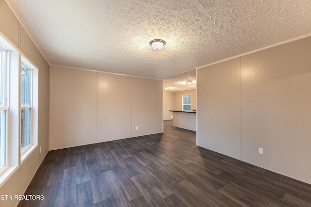 spare room featuring dark wood-type flooring and a textured ceiling