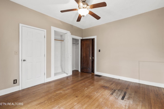 unfurnished bedroom featuring wood-type flooring, two closets, and ceiling fan