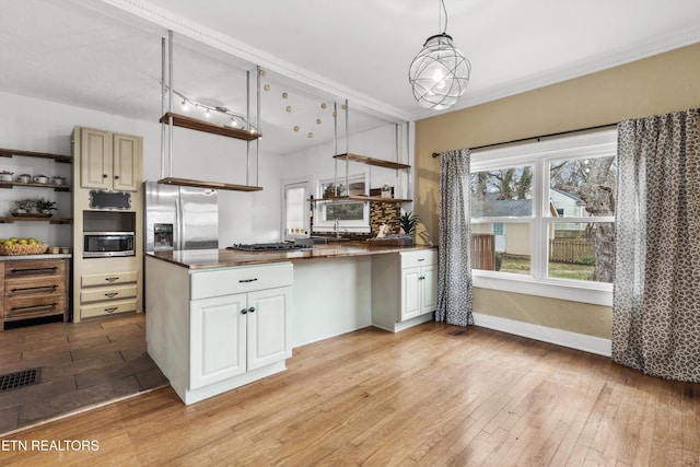 kitchen featuring kitchen peninsula, pendant lighting, stainless steel appliances, and light hardwood / wood-style flooring