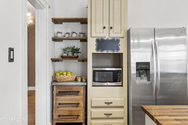 kitchen with cream cabinetry, wood counters, and appliances with stainless steel finishes