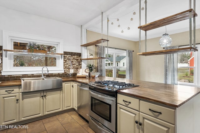 kitchen featuring wood counters, cream cabinets, sink, decorative backsplash, and appliances with stainless steel finishes