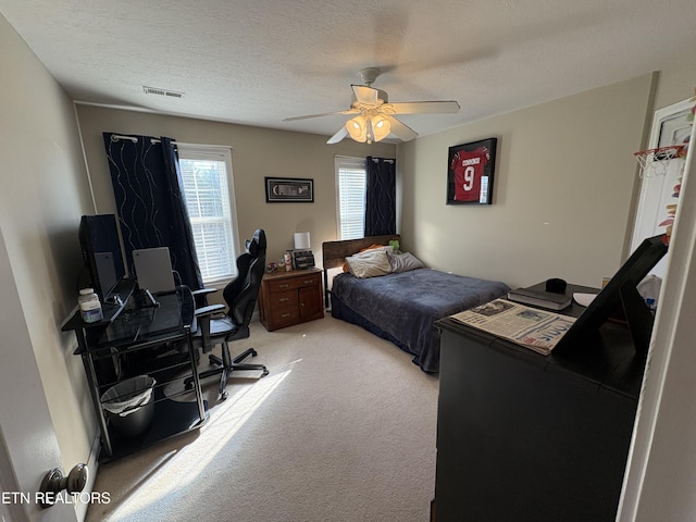 carpeted bedroom featuring ceiling fan and a textured ceiling