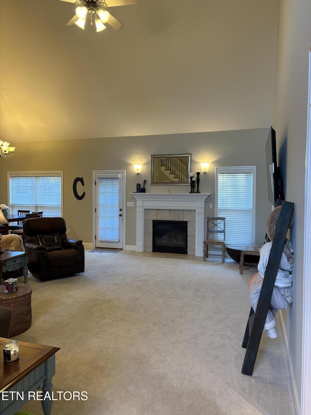 living room with a tile fireplace, light colored carpet, and ceiling fan