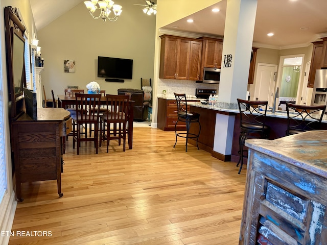 dining room with ornamental molding, lofted ceiling, a chandelier, and light hardwood / wood-style flooring