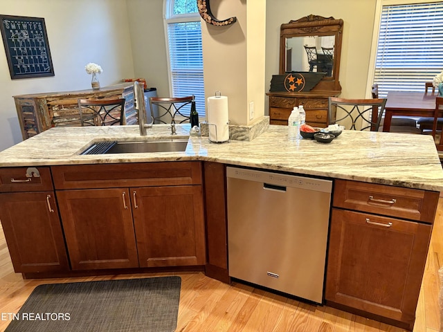 kitchen with sink, light stone counters, light wood-type flooring, dishwasher, and a healthy amount of sunlight