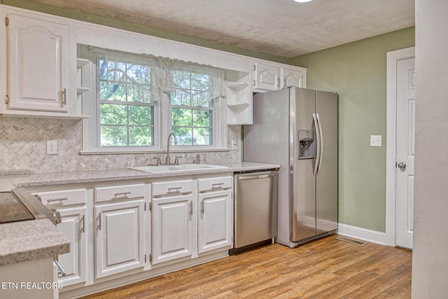 kitchen with white cabinetry, sink, stainless steel appliances, and light wood-type flooring