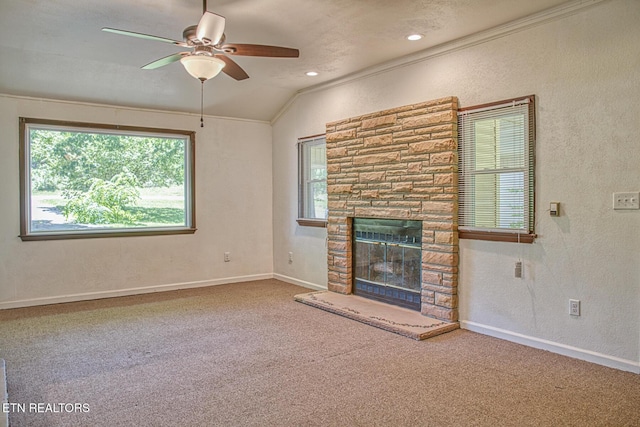 unfurnished living room with ceiling fan, crown molding, carpet floors, a stone fireplace, and lofted ceiling