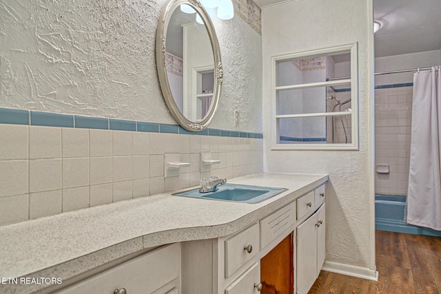 bathroom with hardwood / wood-style flooring, vanity, shower / bath combo with shower curtain, and tile walls