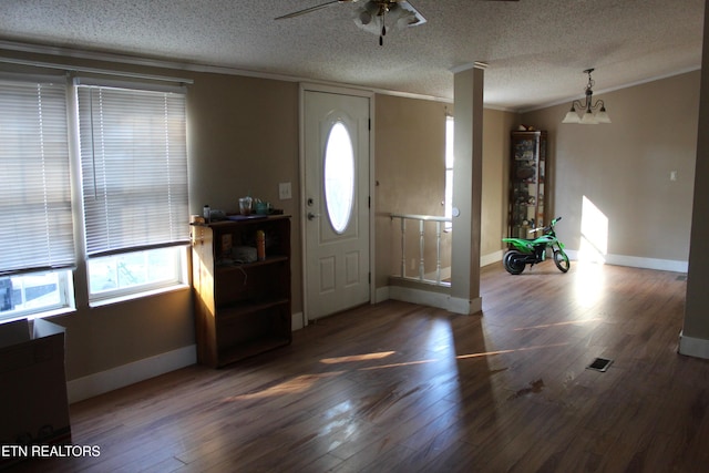 foyer featuring dark hardwood / wood-style flooring, ceiling fan with notable chandelier, a textured ceiling, crown molding, and lofted ceiling