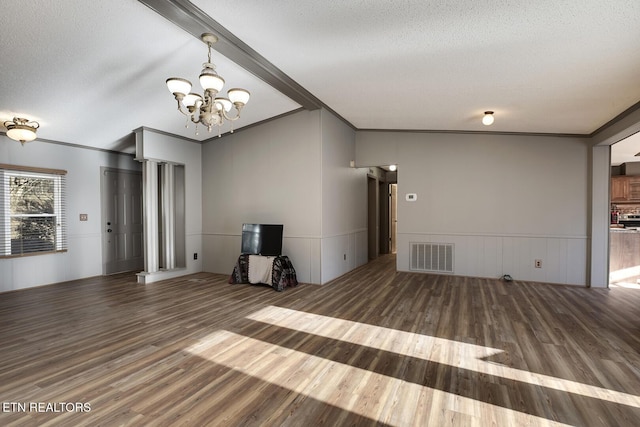 unfurnished living room with lofted ceiling with beams, crown molding, hardwood / wood-style flooring, a textured ceiling, and a notable chandelier