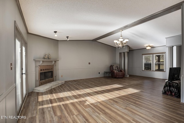 unfurnished living room with a textured ceiling, ornamental molding, vaulted ceiling, and an inviting chandelier