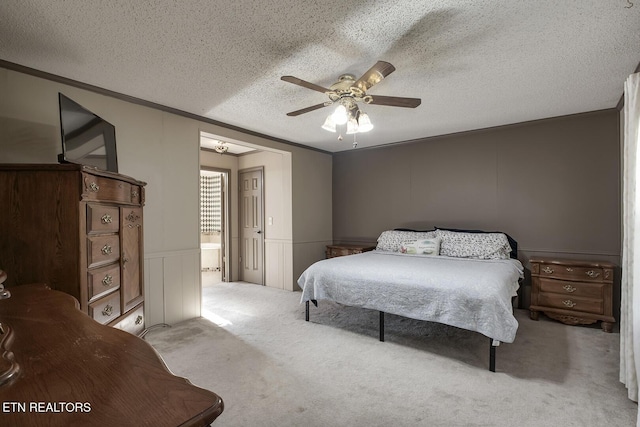 bedroom featuring ceiling fan, ensuite bathroom, a textured ceiling, and light carpet