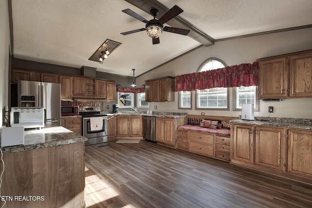 kitchen with vaulted ceiling with beams, dark hardwood / wood-style floors, a textured ceiling, decorative light fixtures, and appliances with stainless steel finishes