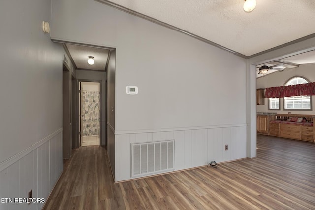 empty room featuring hardwood / wood-style flooring, ceiling fan, ornamental molding, and a textured ceiling