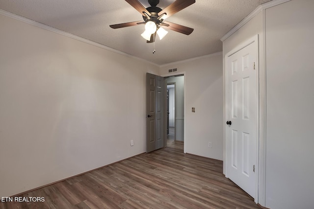 unfurnished bedroom featuring hardwood / wood-style floors, a textured ceiling, ceiling fan, and crown molding