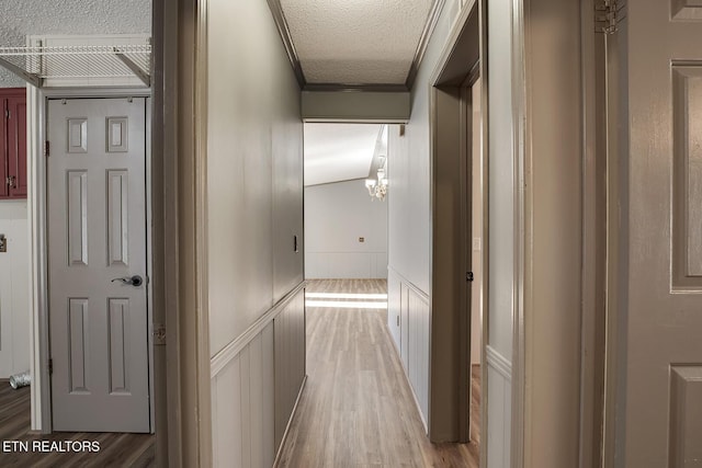 hall featuring hardwood / wood-style floors, a textured ceiling, and crown molding