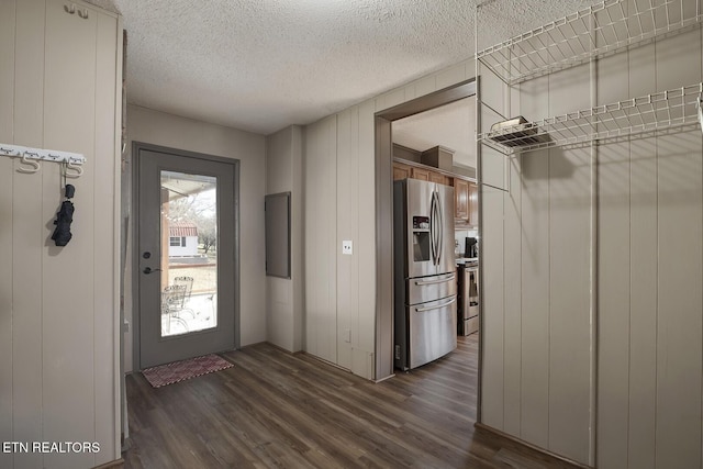 entryway with wood walls, dark wood-type flooring, and a textured ceiling