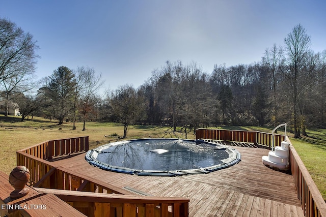 wooden deck with a lawn and a covered pool