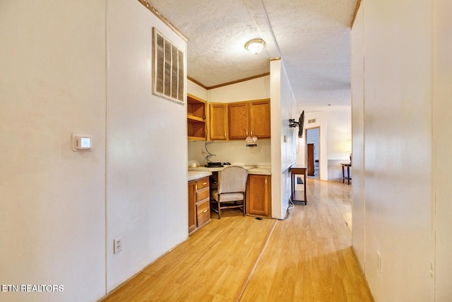 corridor featuring a textured ceiling, light hardwood / wood-style flooring, lofted ceiling, and crown molding