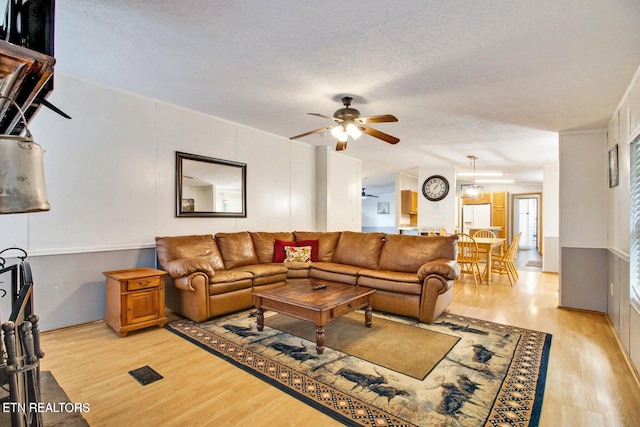 living room featuring ceiling fan, a textured ceiling, and light hardwood / wood-style flooring