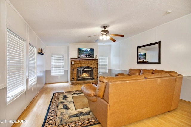 living room featuring a textured ceiling, light wood-type flooring, and ceiling fan