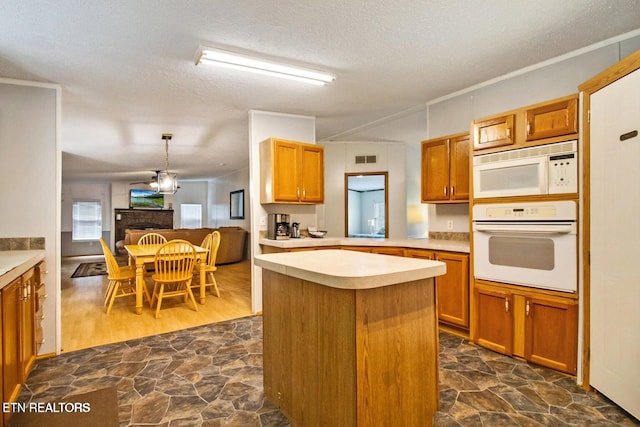 kitchen with pendant lighting, a center island, white appliances, a textured ceiling, and a chandelier