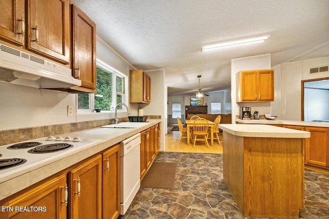 kitchen with sink, pendant lighting, a textured ceiling, white appliances, and a kitchen island