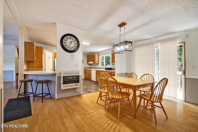 dining area with a textured ceiling, heating unit, crown molding, and light hardwood / wood-style floors