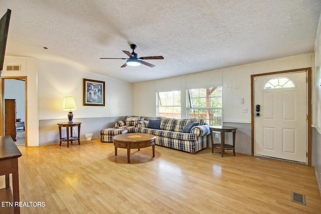 living room featuring a textured ceiling, light hardwood / wood-style flooring, ceiling fan, and vaulted ceiling