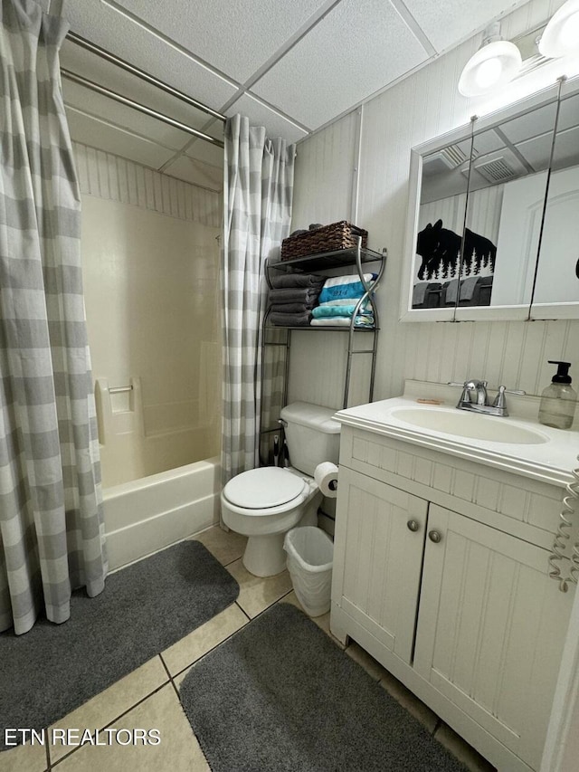 full bathroom with a paneled ceiling, vanity, shower / tub combo with curtain, tile patterned flooring, and toilet