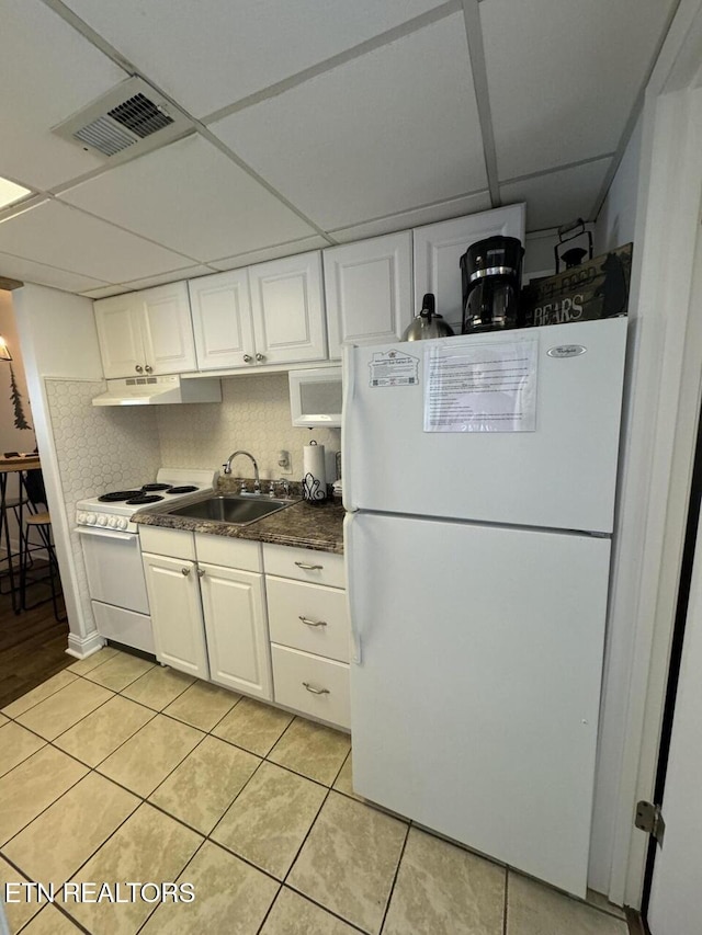 kitchen featuring backsplash, a paneled ceiling, white appliances, white cabinets, and light tile patterned flooring