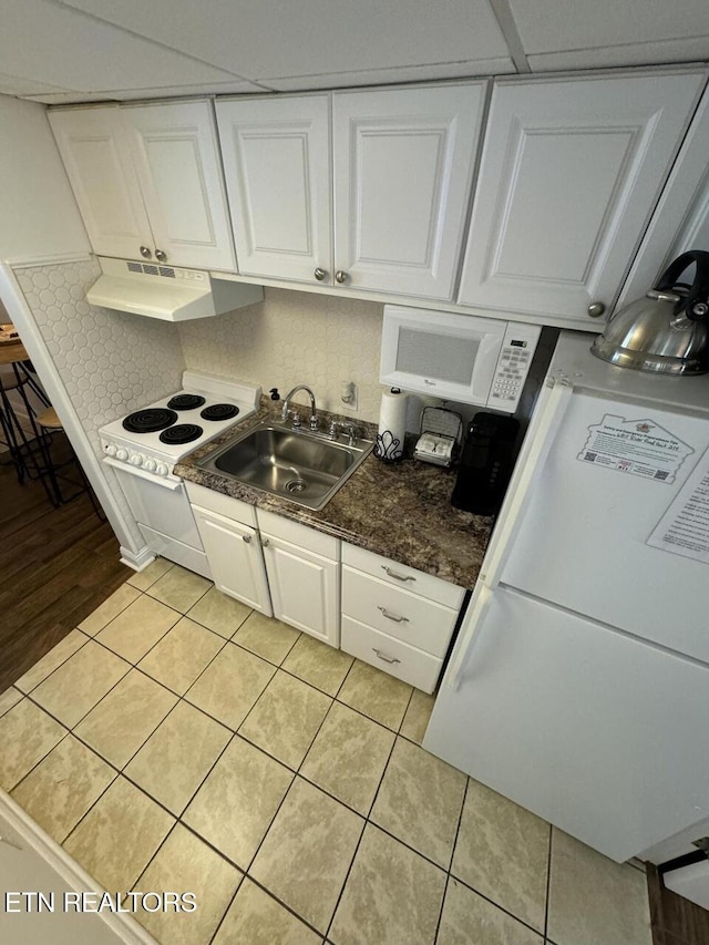 kitchen with white appliances, exhaust hood, white cabinets, sink, and light tile patterned flooring