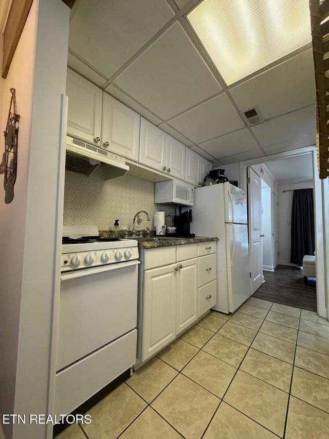 kitchen featuring a paneled ceiling, white appliances, sink, light tile patterned floors, and white cabinets