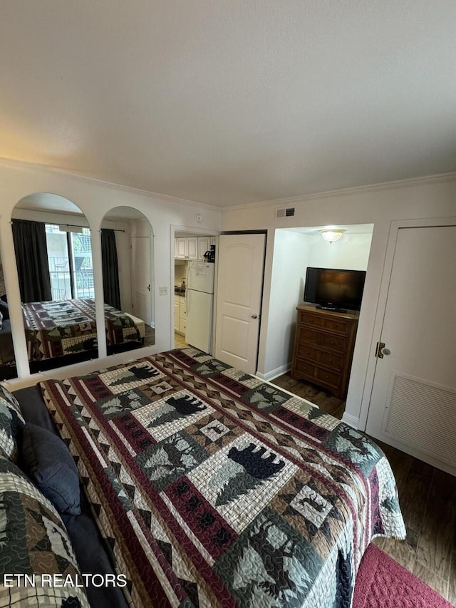 bedroom featuring dark hardwood / wood-style flooring, white fridge, and crown molding