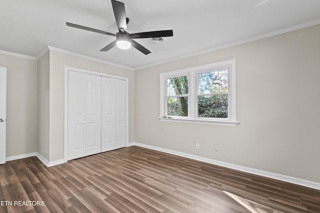 unfurnished bedroom featuring ceiling fan, dark hardwood / wood-style flooring, ornamental molding, and a closet