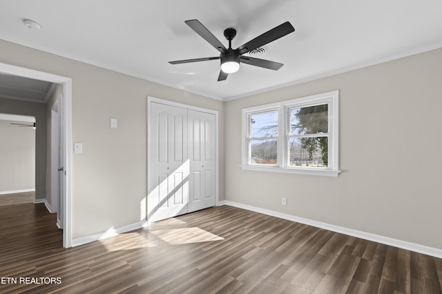 unfurnished bedroom featuring ceiling fan, dark hardwood / wood-style floors, crown molding, and a closet