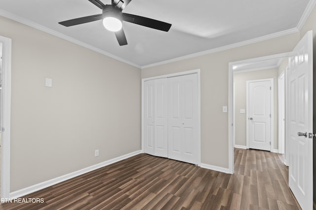 unfurnished bedroom with ceiling fan, dark wood-type flooring, crown molding, and a closet