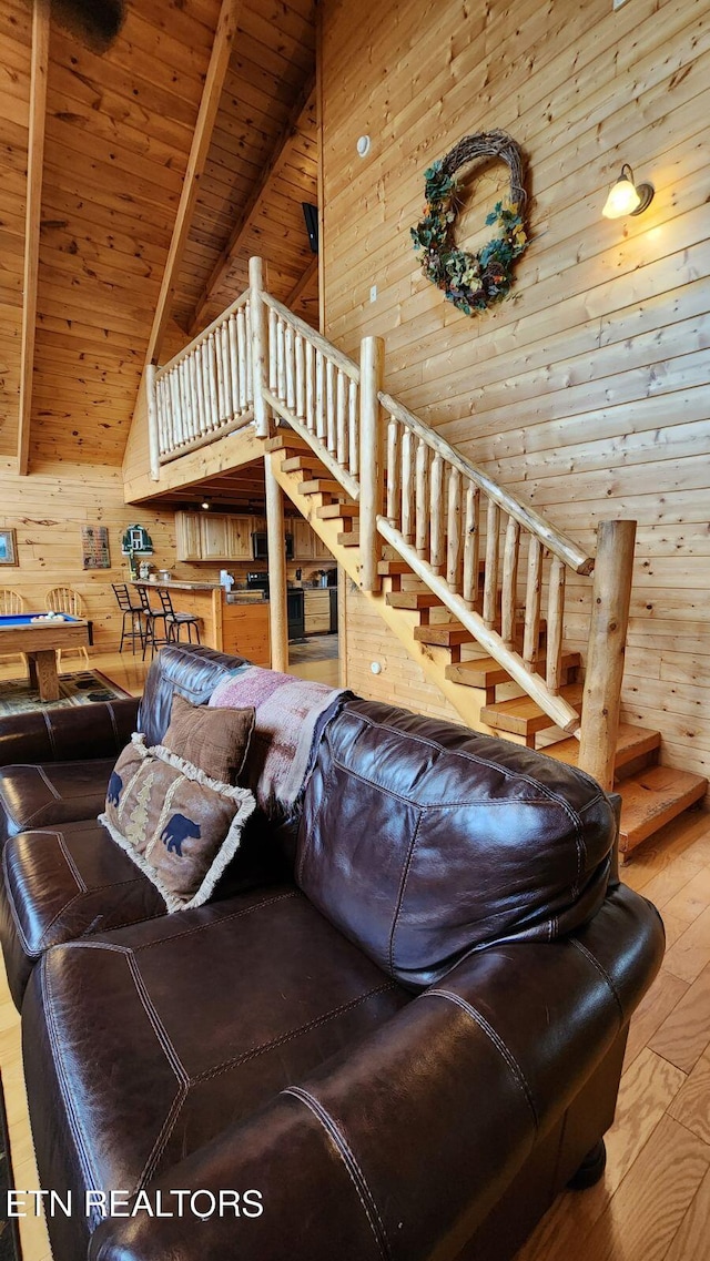 living room featuring wood ceiling, beam ceiling, hardwood / wood-style flooring, high vaulted ceiling, and wood walls