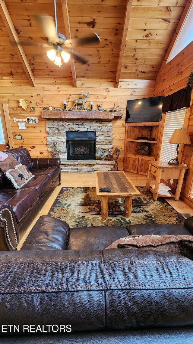 living room with vaulted ceiling with beams, wooden walls, a fireplace, and wooden ceiling