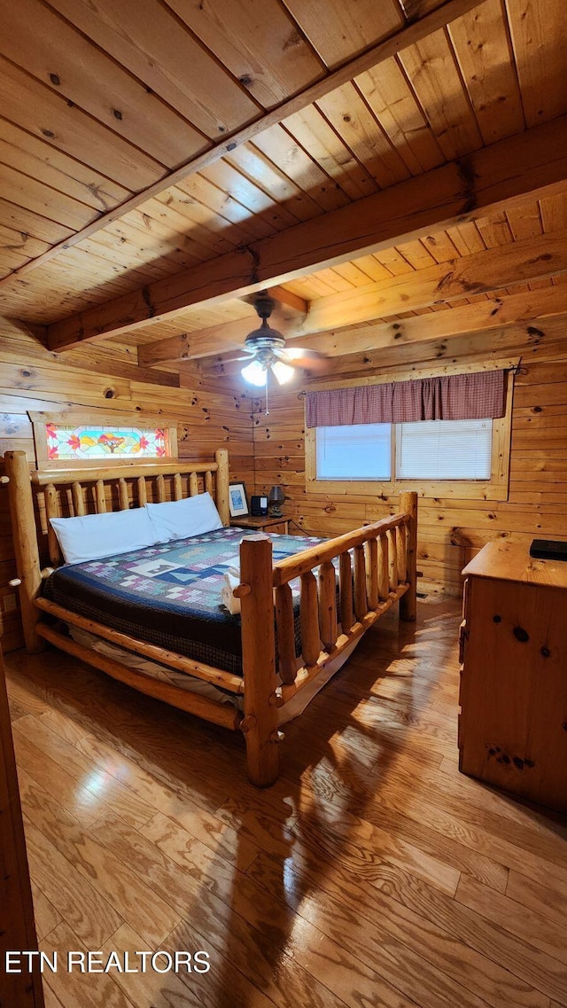 bedroom with beamed ceiling, wood walls, wood ceiling, and light hardwood / wood-style floors