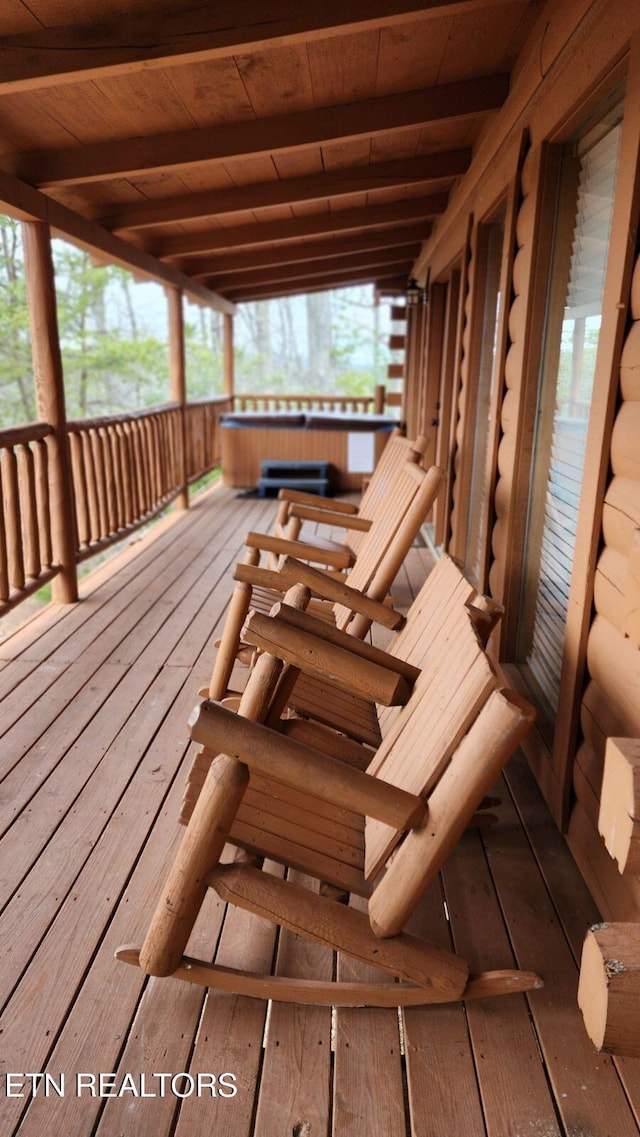 wooden terrace featuring a porch and a hot tub