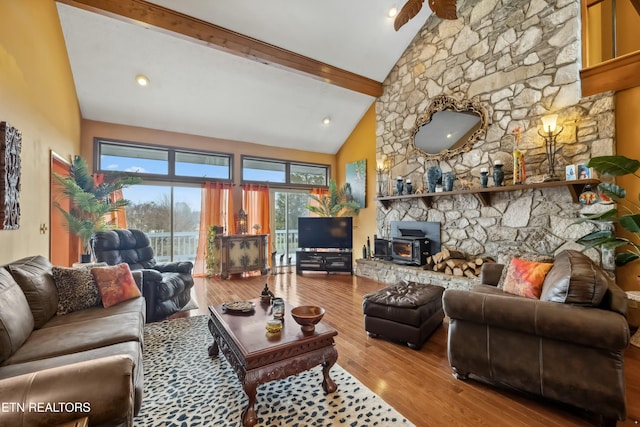 living room with beamed ceiling, a wood stove, high vaulted ceiling, and light hardwood / wood-style flooring