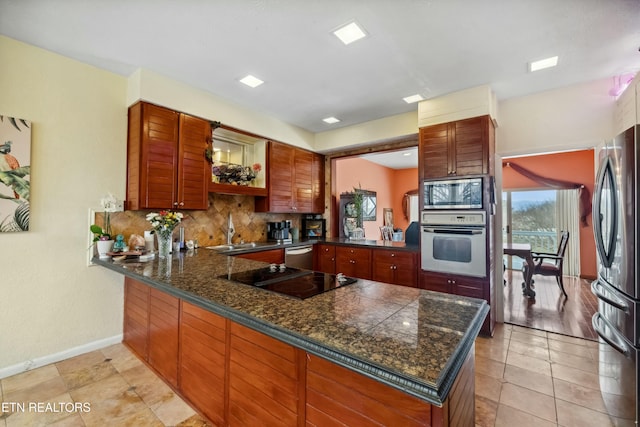 kitchen featuring sink, tasteful backsplash, kitchen peninsula, light tile patterned floors, and appliances with stainless steel finishes